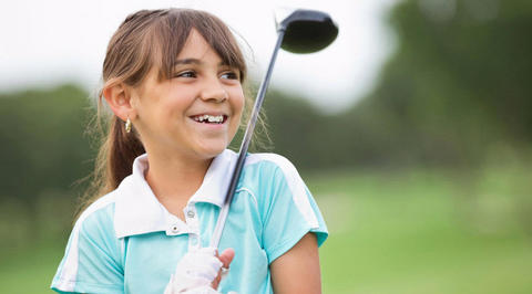 Young girl holding a golf driver and smiling