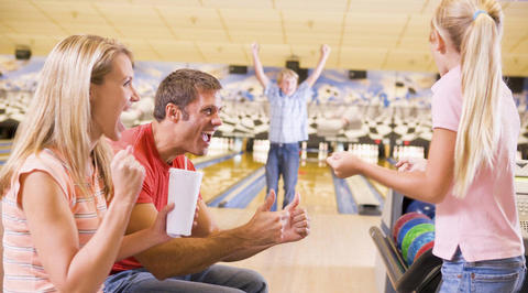 Father and children celebrating while bowling