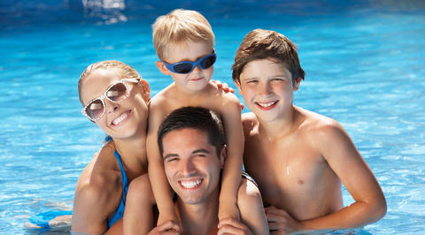 Family of 4 smiling in the swimming pool