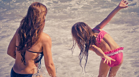 Mother and daughter playing in shallow ocean water