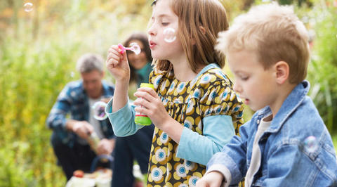 Girl blowing bubbles with her family
