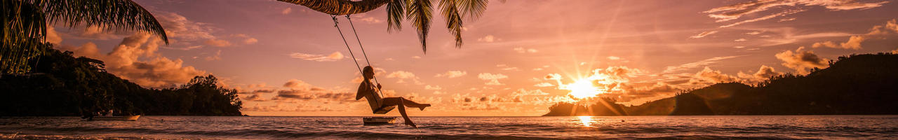 Woman sitting on swing in front of ocean