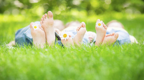 Group of 3 people lying on the ground with daisies between toes
